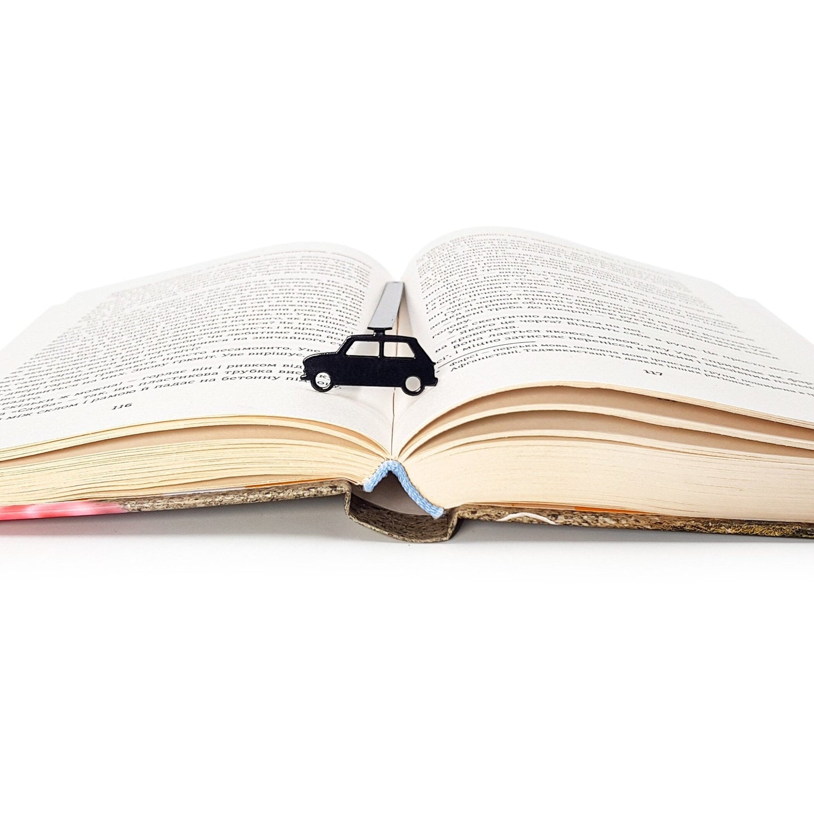 Black Car metal bookmark resting on the pages of an open book