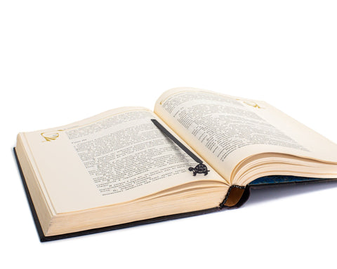 Turtle metal bookmark resting on the pages of an open book