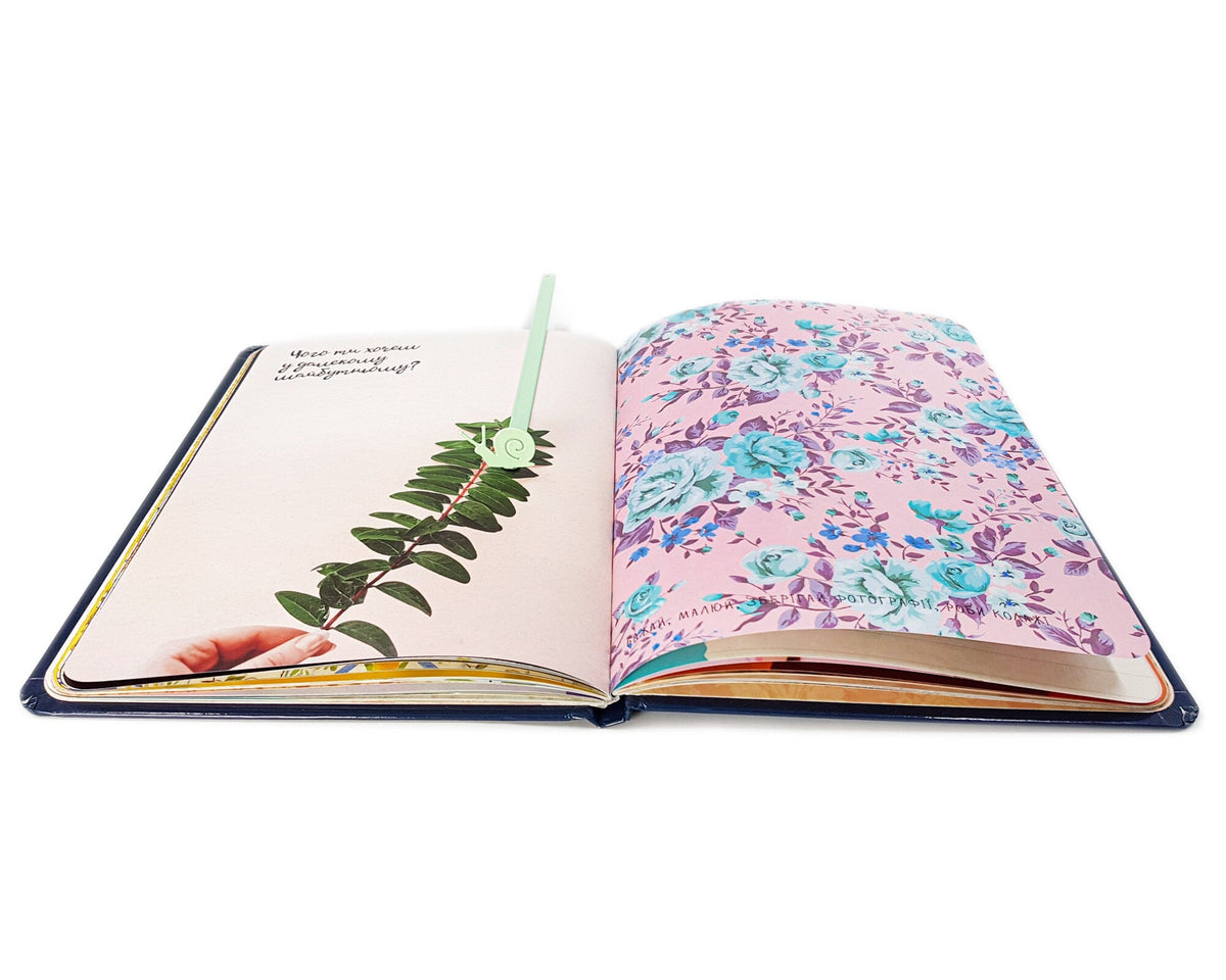 Snail metal bookmark in green marking a page in an illustrated book