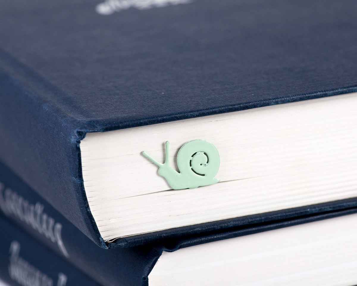 Snail metal bookmark in green seen from the edge of a closed book
