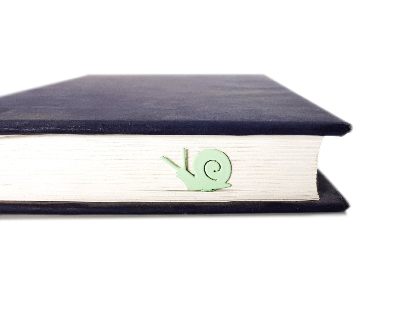 Snail metal bookmark in green clipped in a closed book, viewed from the side