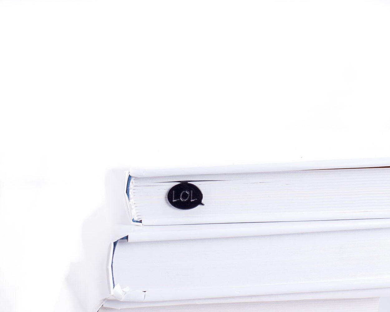 Speech Bubble LOL metal bookmark seen from the edge of a closed book