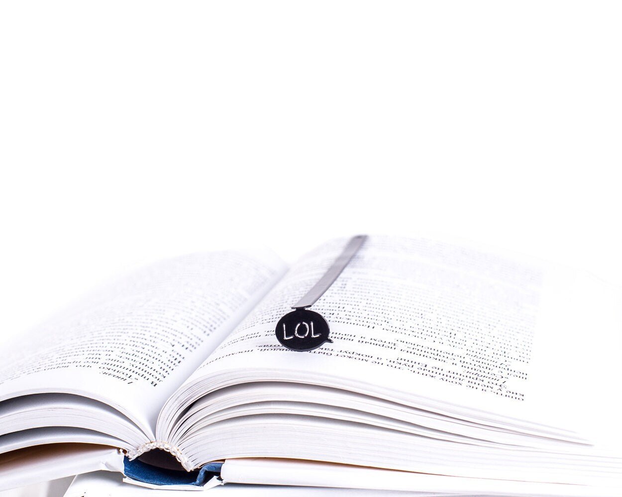 Speech Bubble LOL metal bookmark resting on the pages of an open book