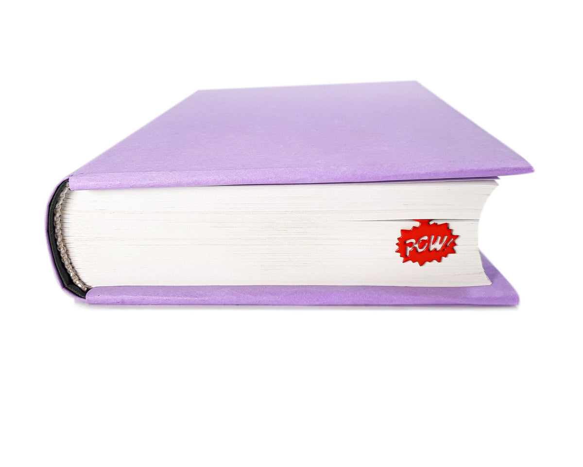 Speech Bubble Pow metal bookmark in red clipped in a closed book, viewed from the side