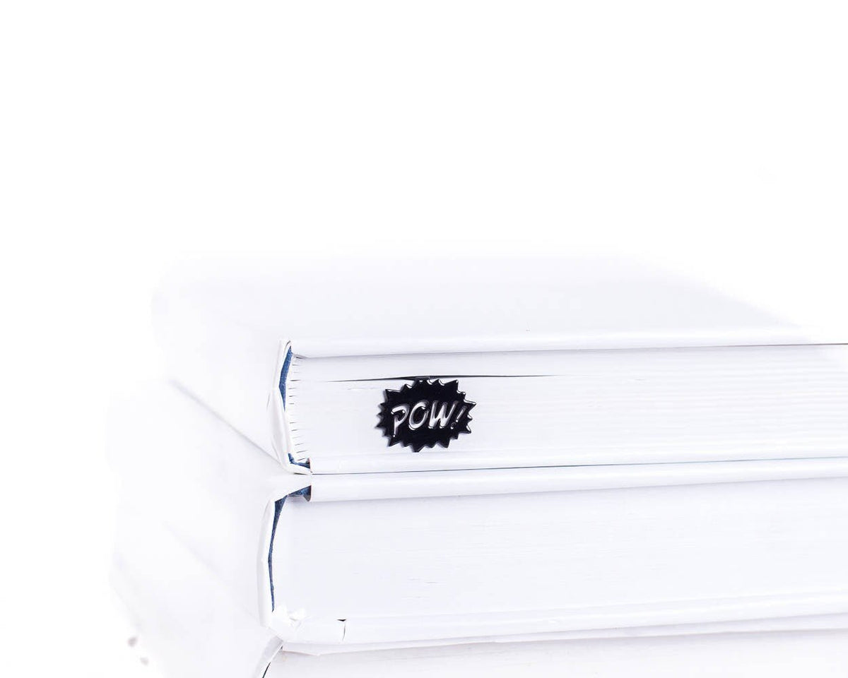 Speech Bubble Pow metal bookmark in red shown with a stack of books
