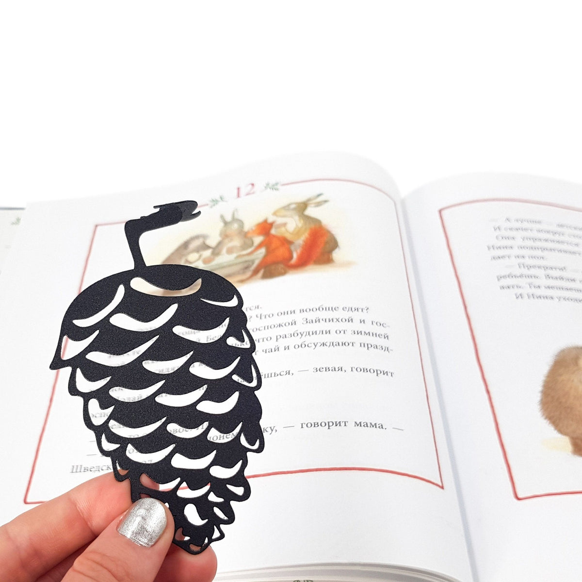 Squirrel and a Pinecone metal bookmark resting on the pages of an open book