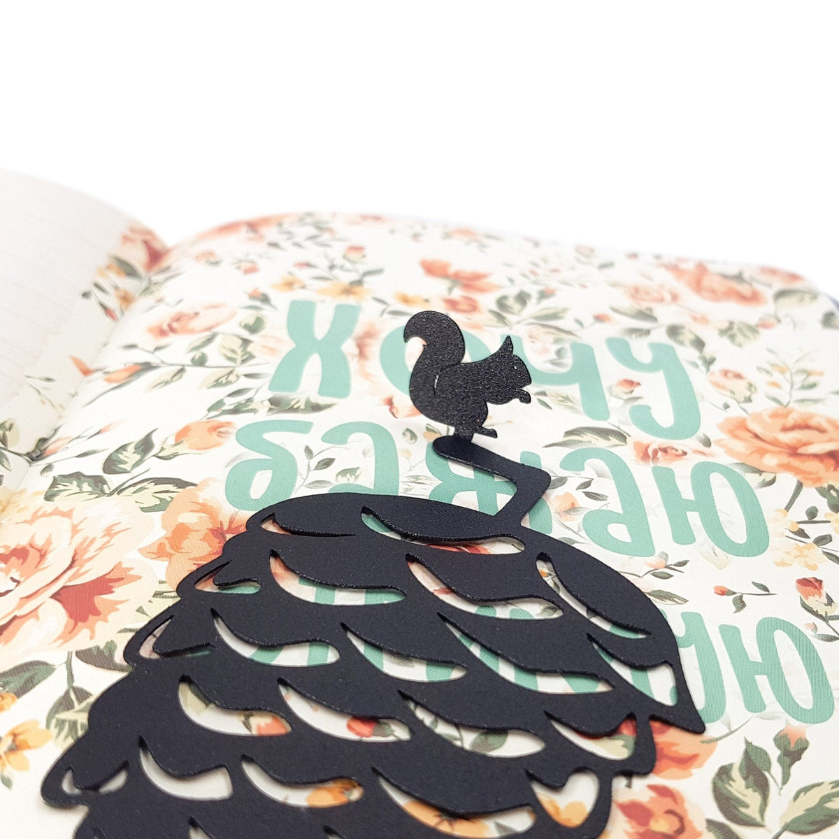 Squirrel and a Pinecone metal bookmark marking a page in an illustrated book