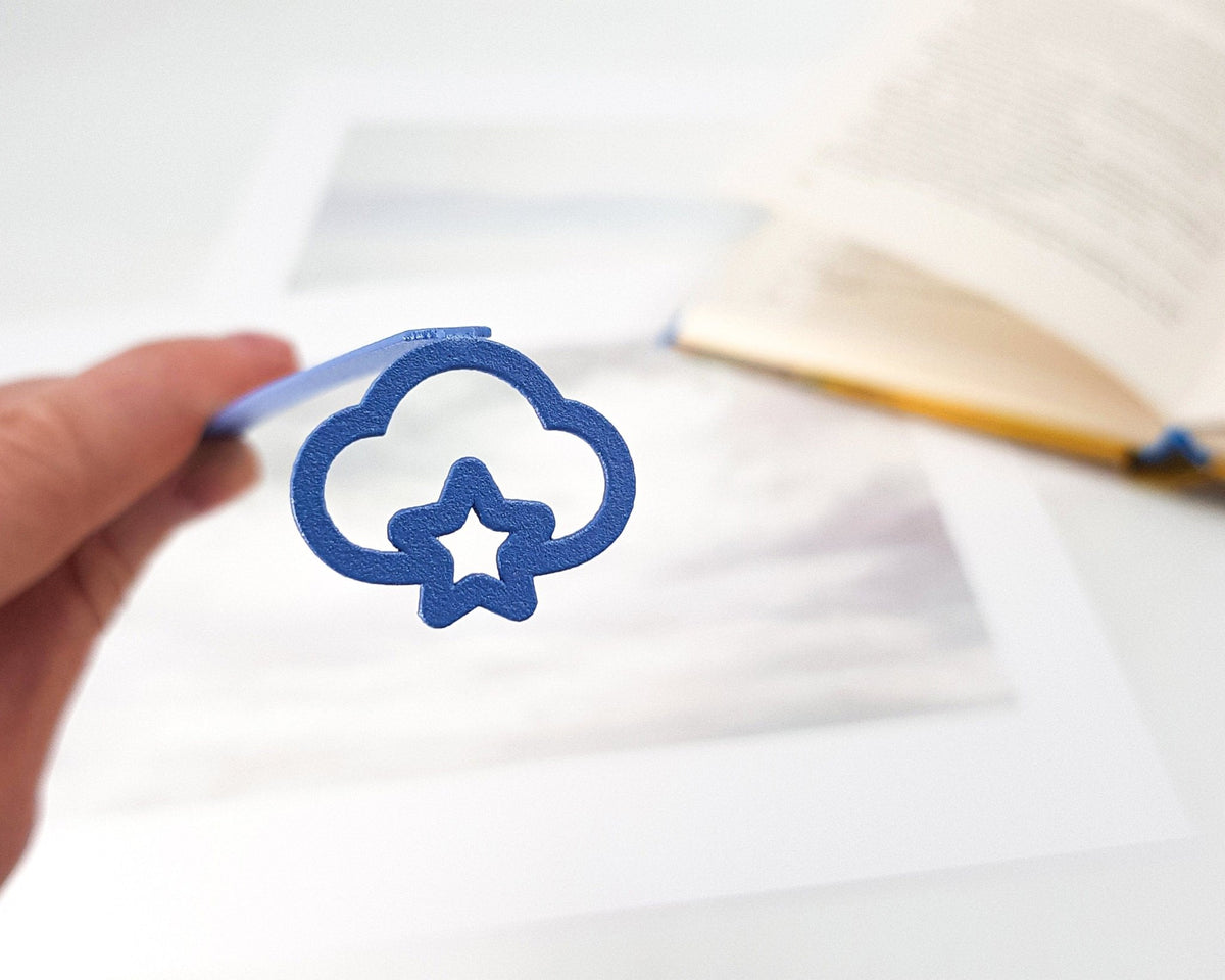 Star Cloud metal bookmark in blue resting on the pages of an open book
