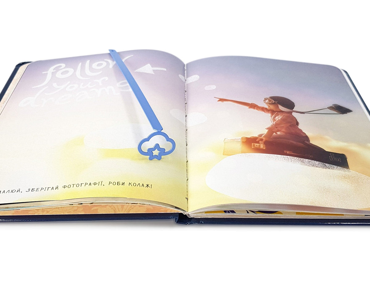 Star Cloud metal bookmark in blue on an illustrated page