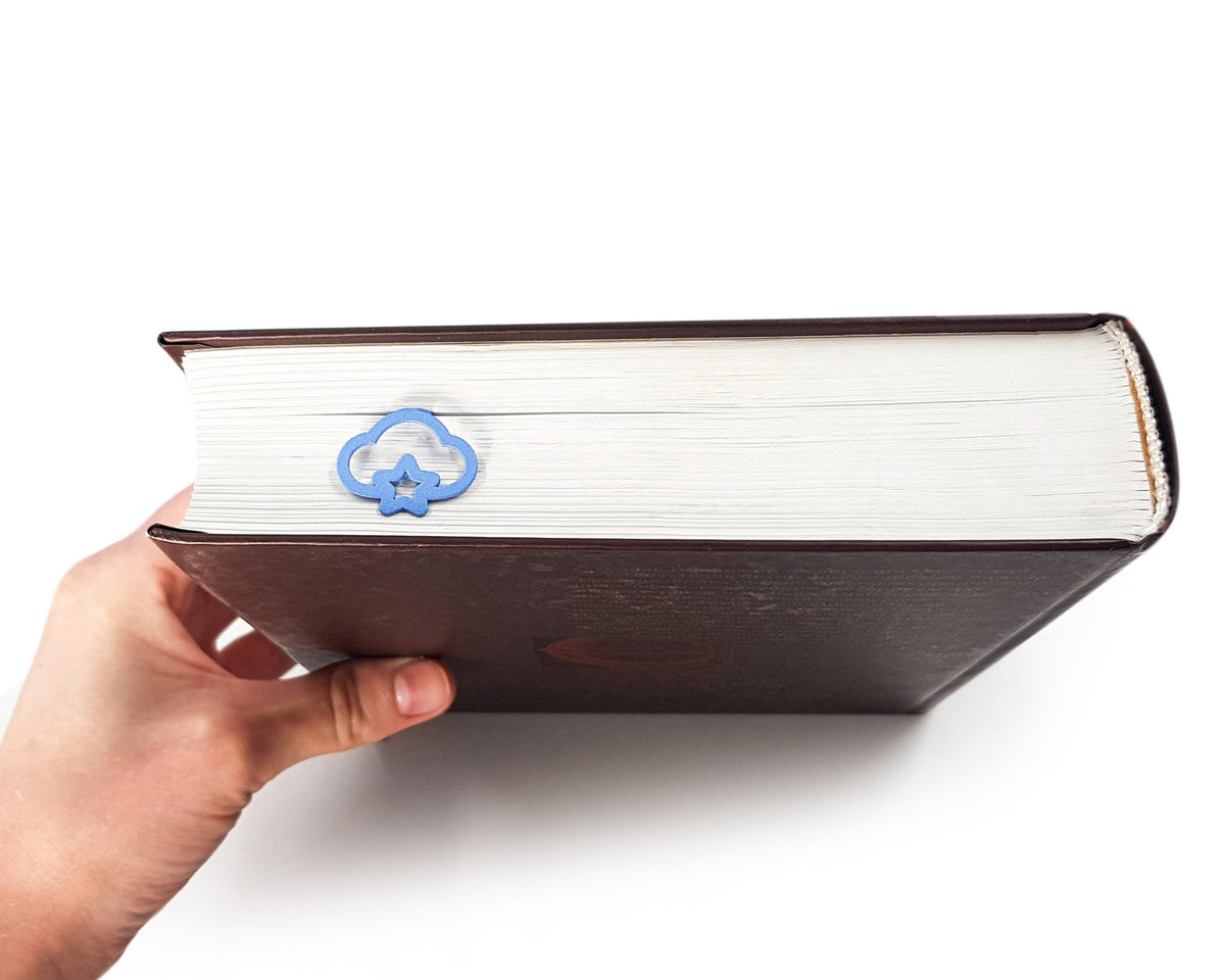 Star Cloud metal bookmark in blue in a closed book, only its top showing above the pages