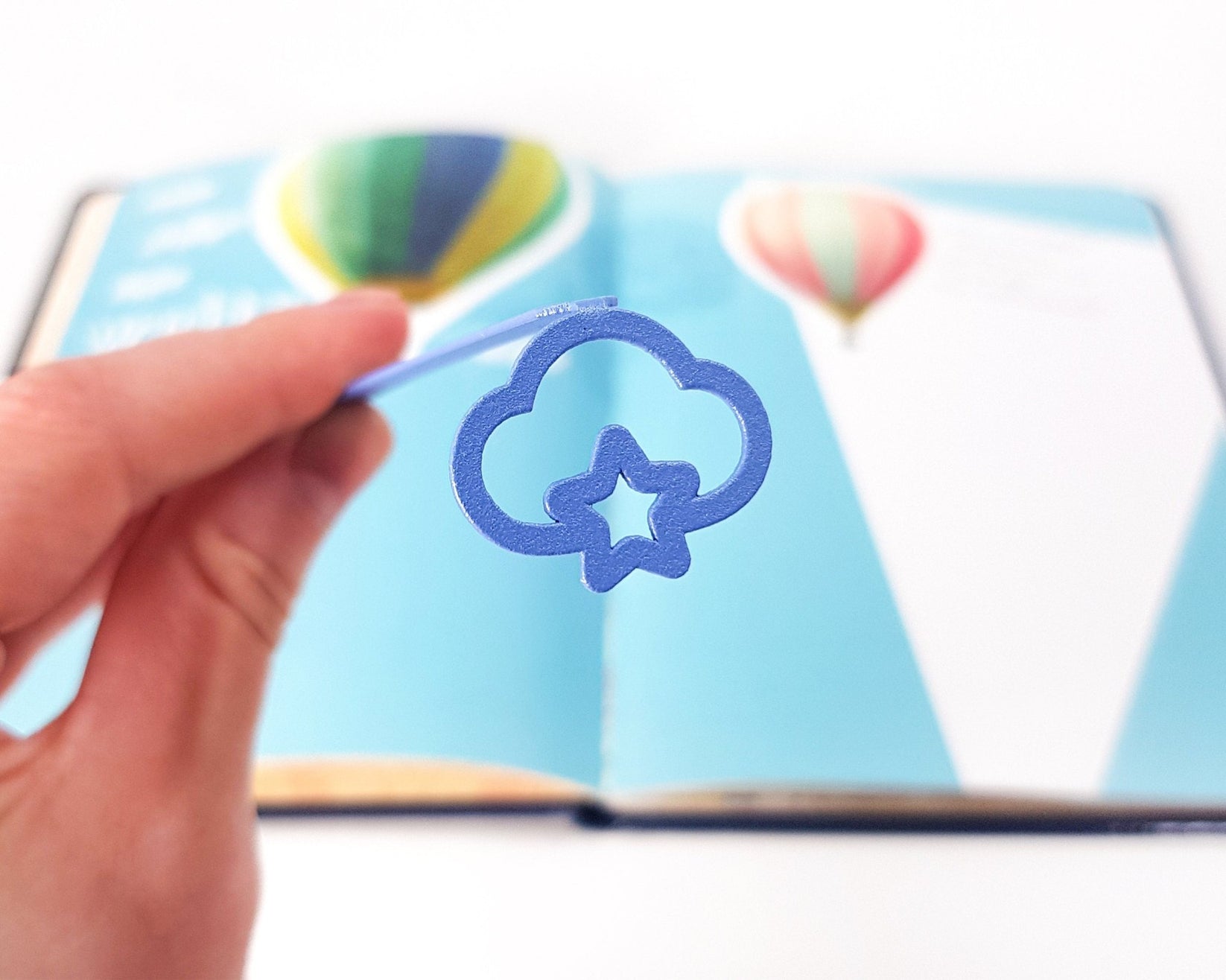Star Cloud metal bookmark in blue marking a page in an illustrated book