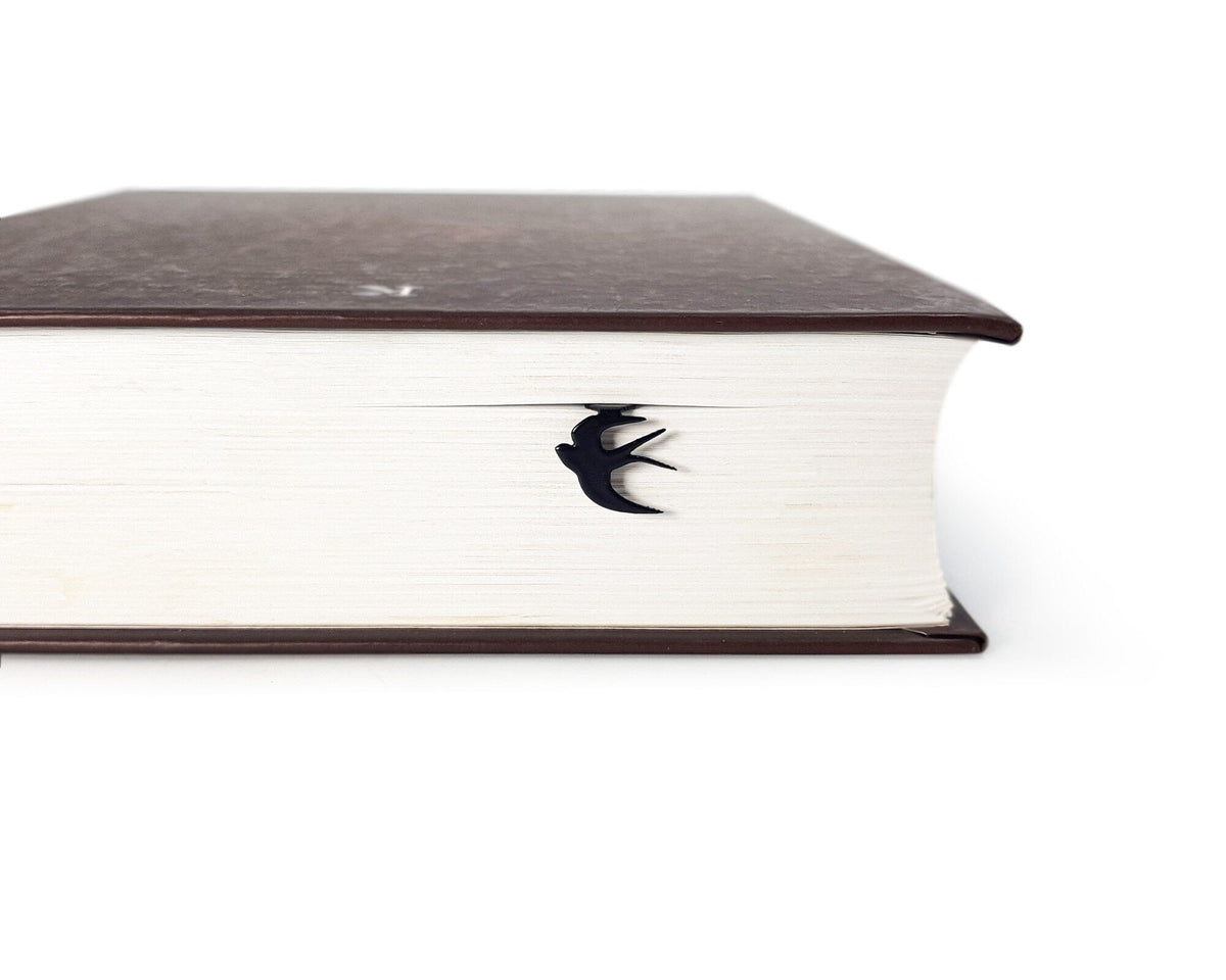 Swallow metal bookmark in a closed book, only its top showing above the pages