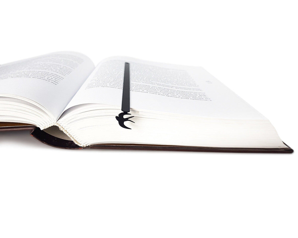 Swallow metal bookmark resting on the pages of an open book