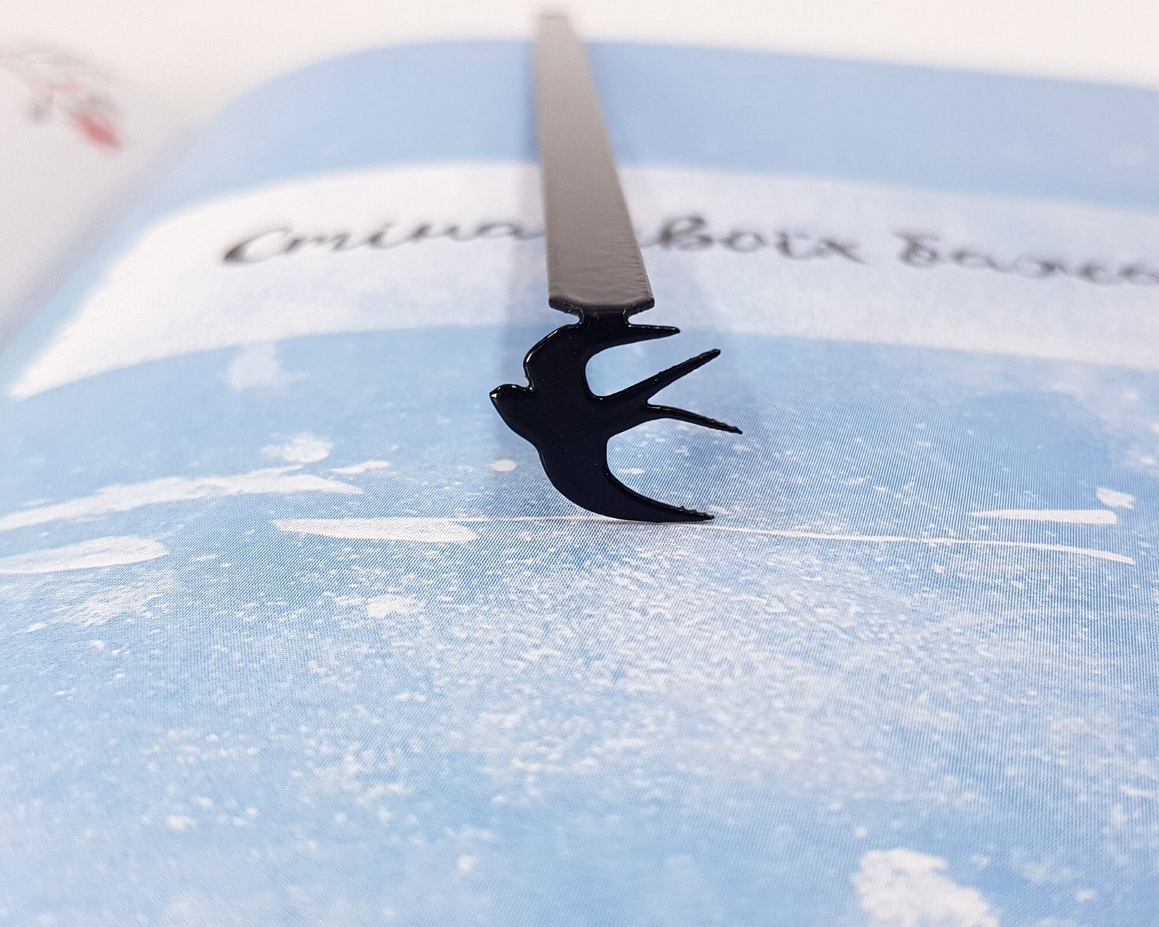 Swallow metal bookmark on a coloured background