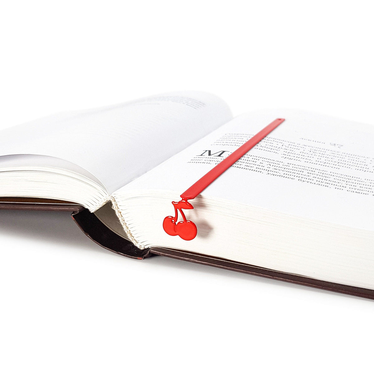 Sweet Cherries metal bookmark in red marking a page in an open book