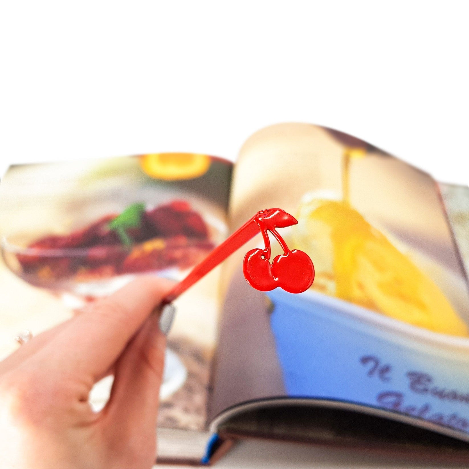 Sweet Cherries metal bookmark in red marking a page in an illustrated book