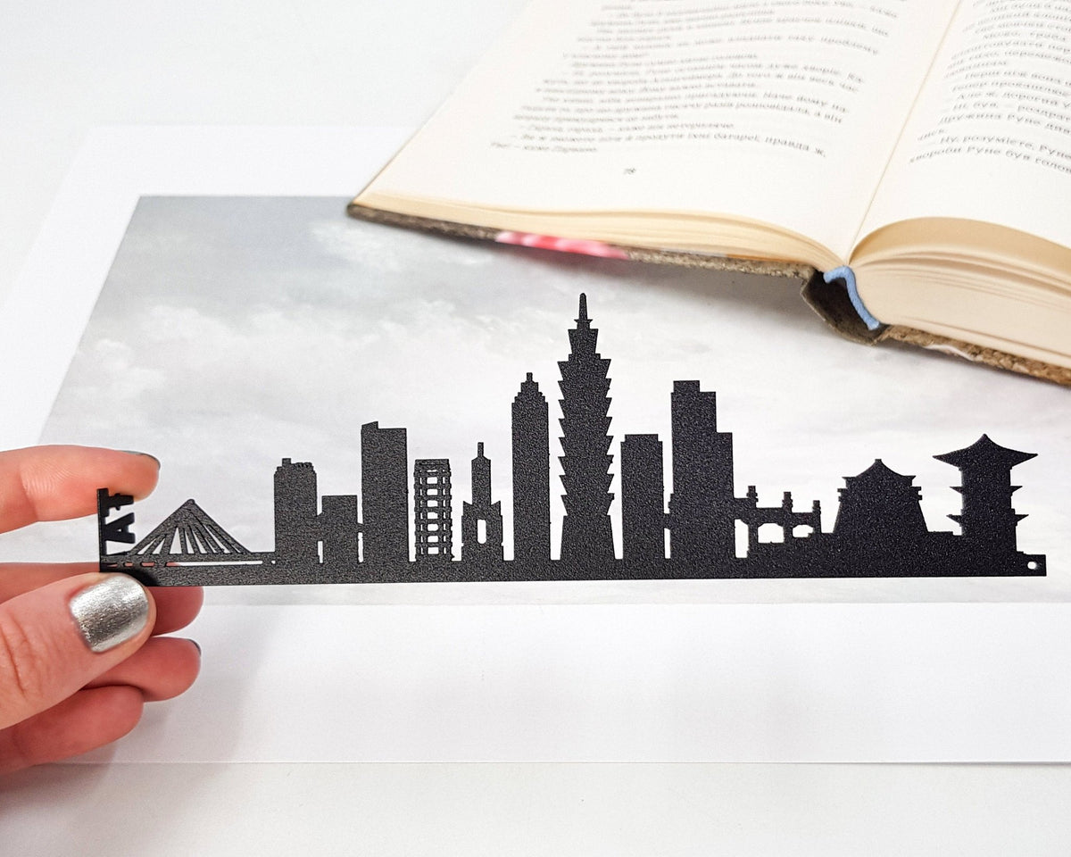 Taipei metal bookmark held in a hand above an open book