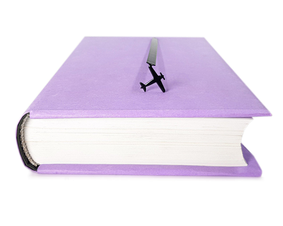 Take a Book Will Fly metal bookmark marking a place in a closed book