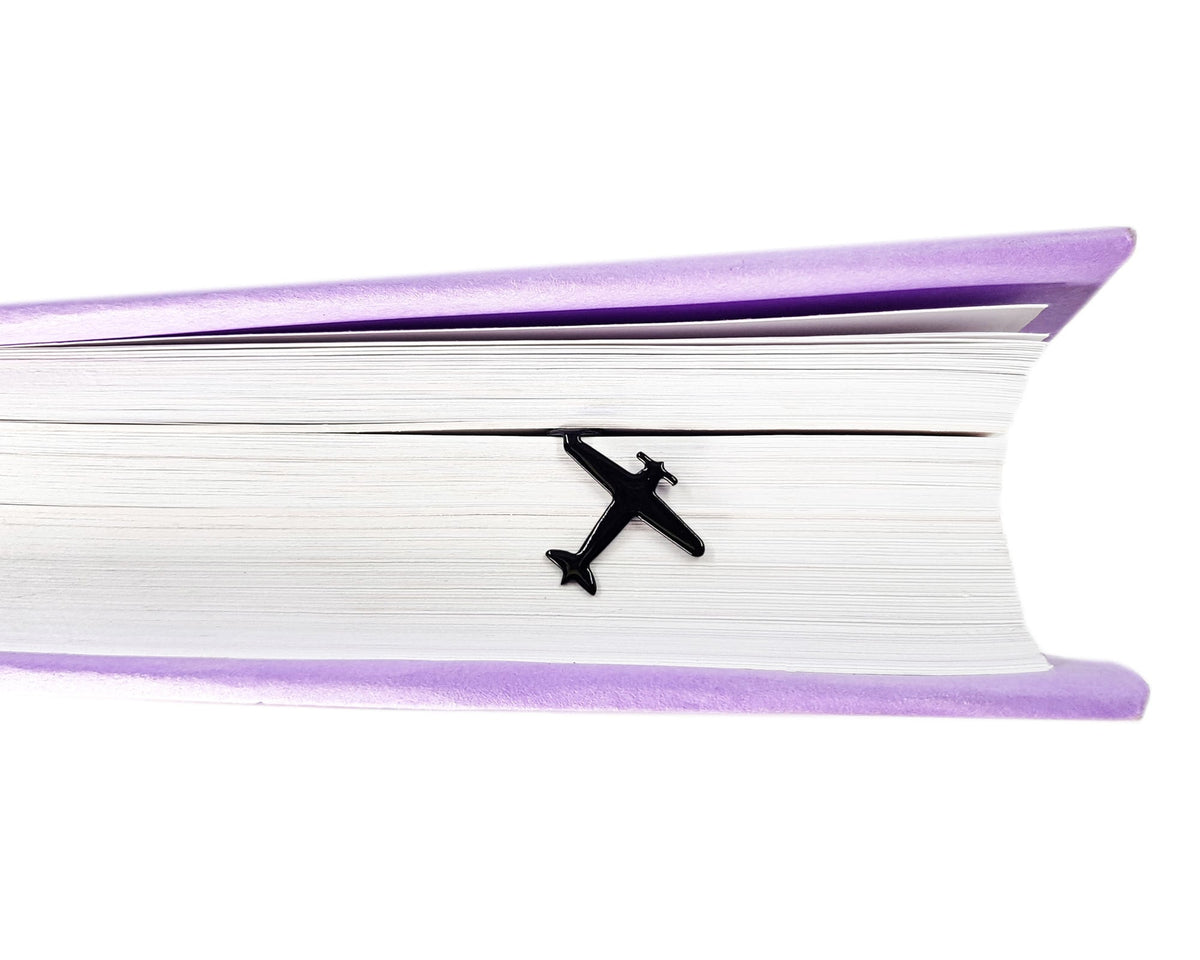 Take a Book Will Fly metal bookmark clipped in a closed book, viewed from the side