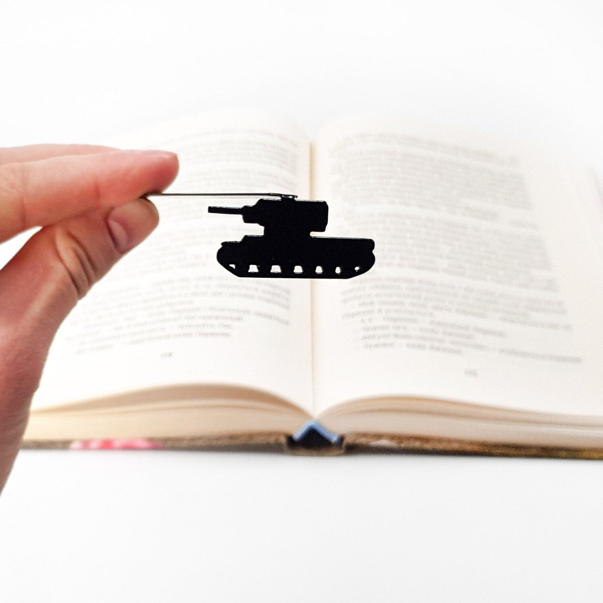 Tank metal bookmark held in a hand above an open book