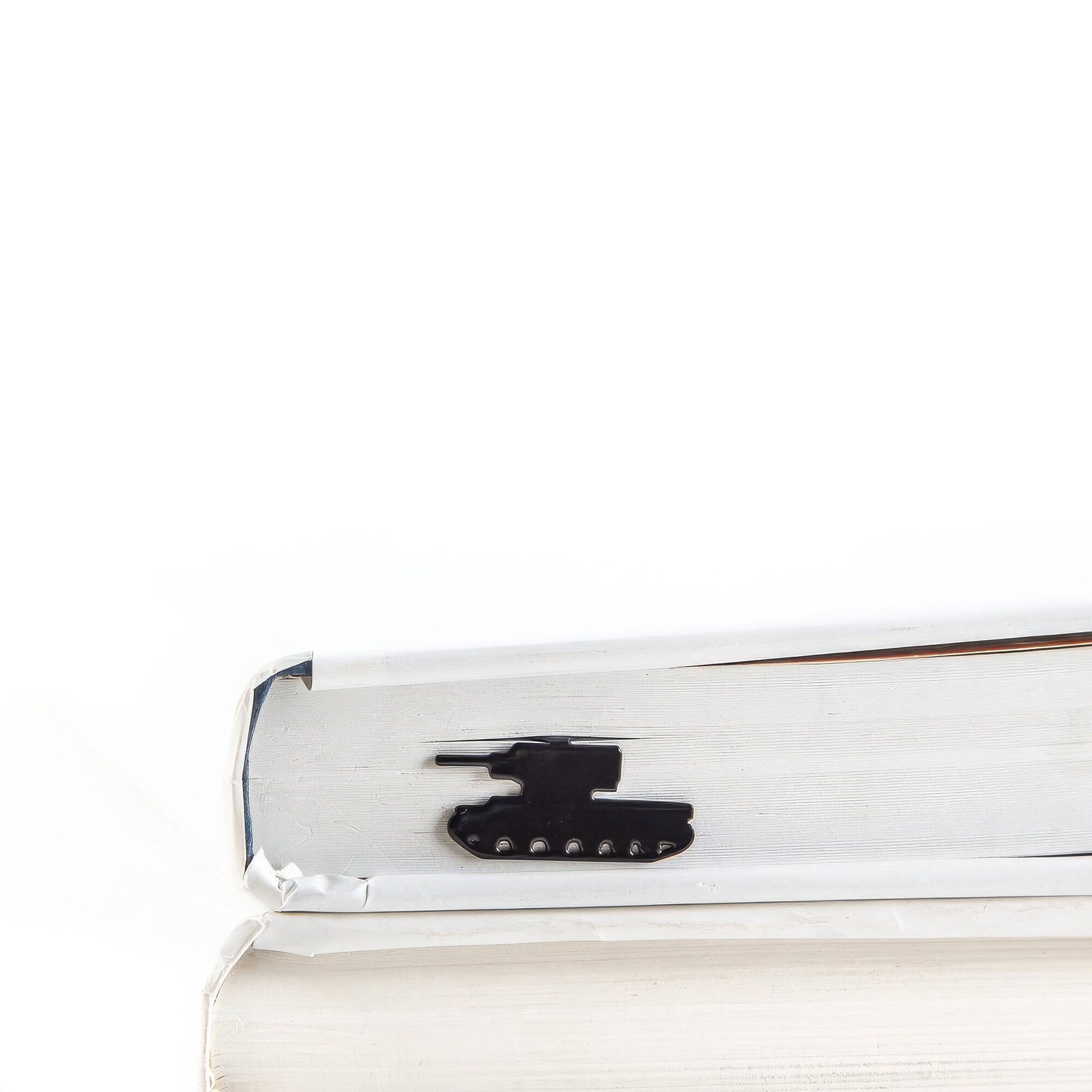 Tank metal bookmark in a closed book, only its top showing above the pages
