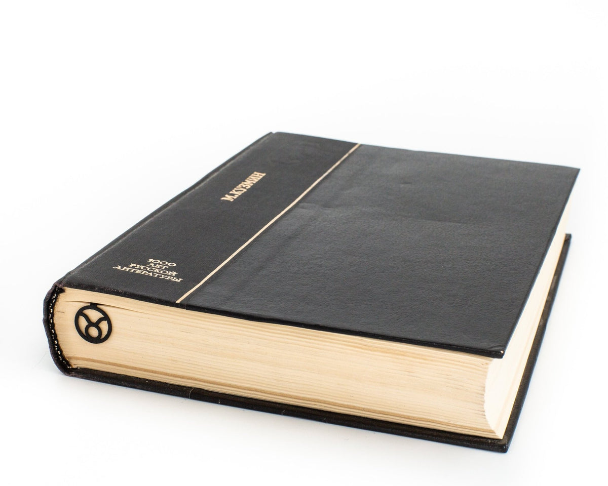 Taurus metal bookmark in a closed book, only its top showing above the pages