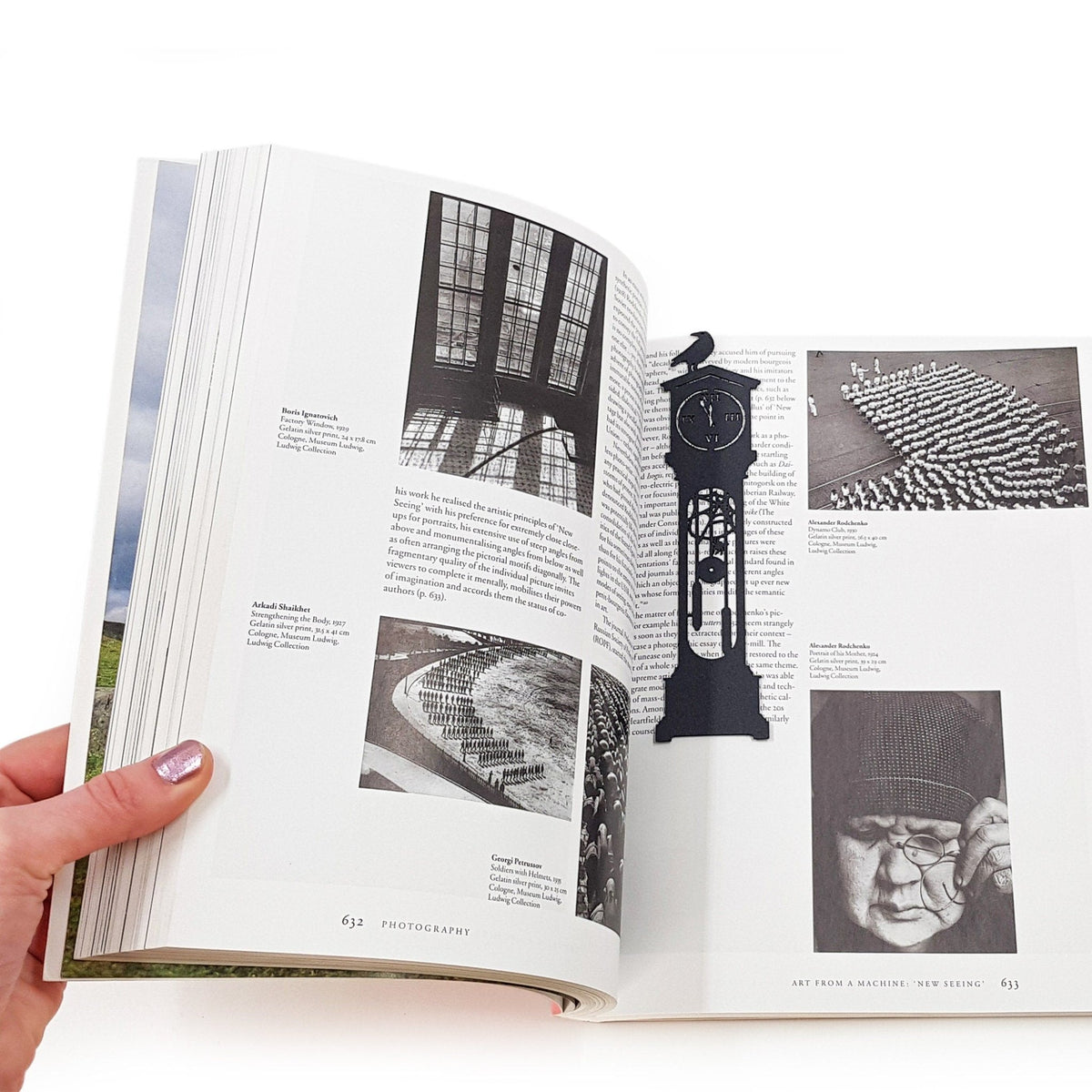 The Raven's Pendulum Dance metal bookmark held over a book, seen from the front