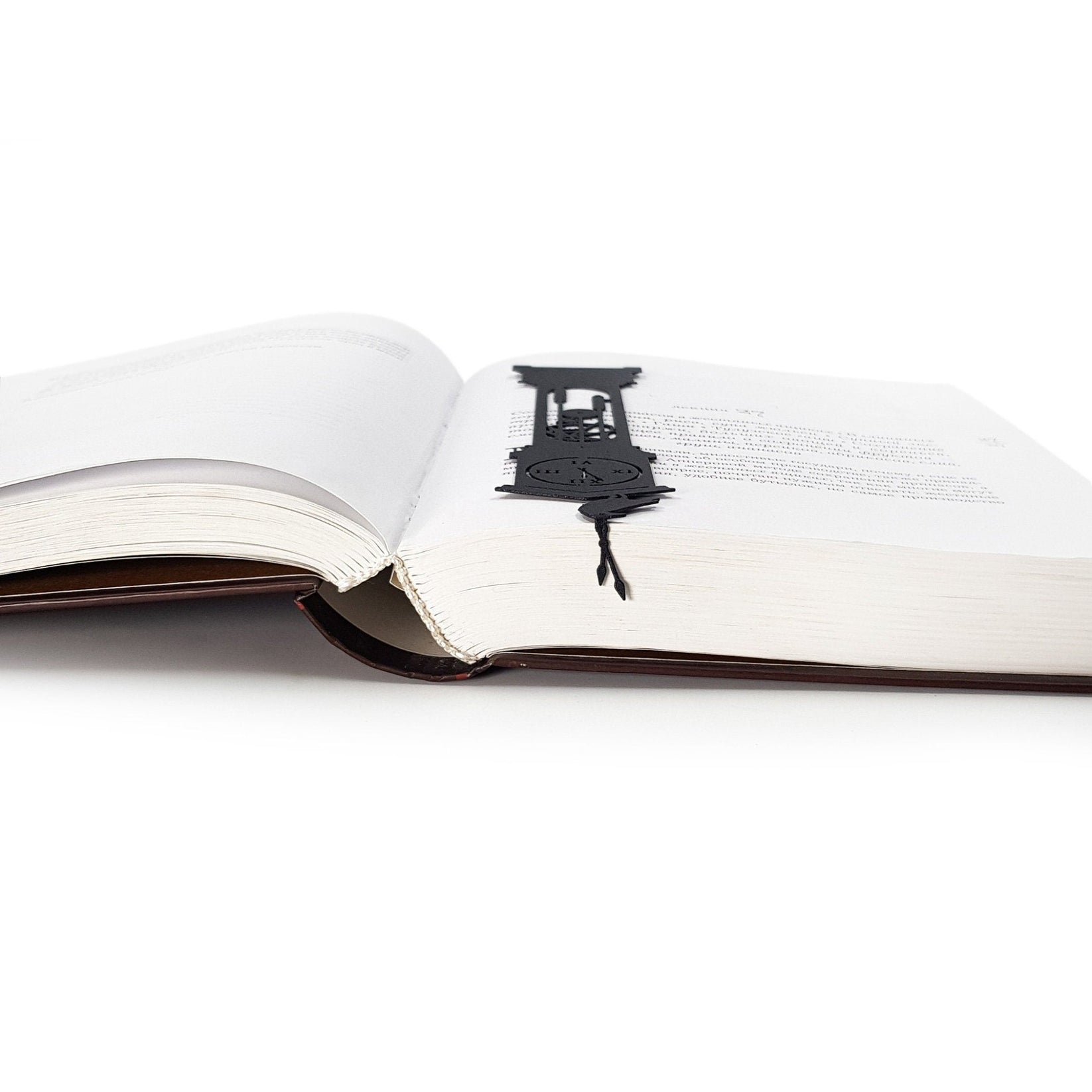 The Raven's Pendulum Dance metal bookmark marking a page in an open book