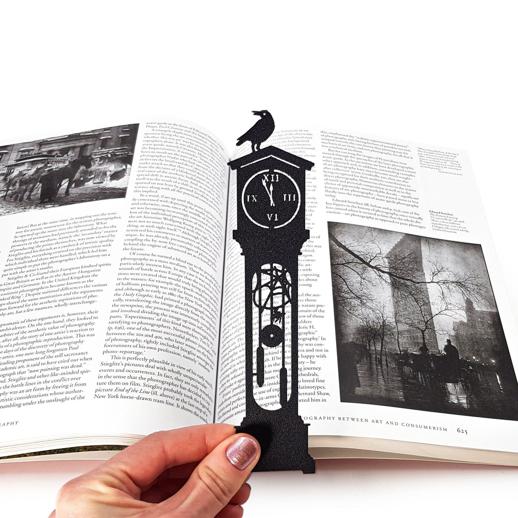 The Raven's Pendulum Dance metal bookmark held in a hand to show its size