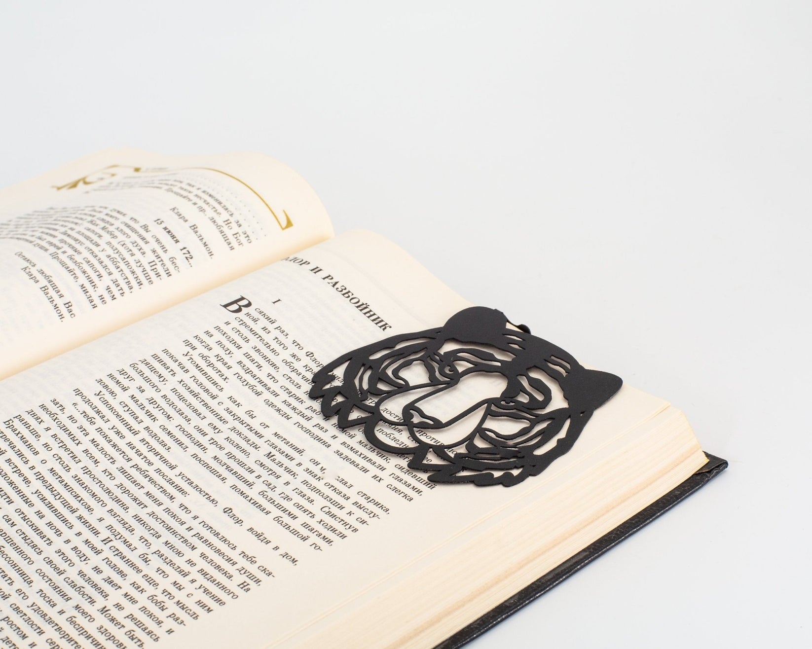 Tiger Head metal bookmark resting on the pages of an open book