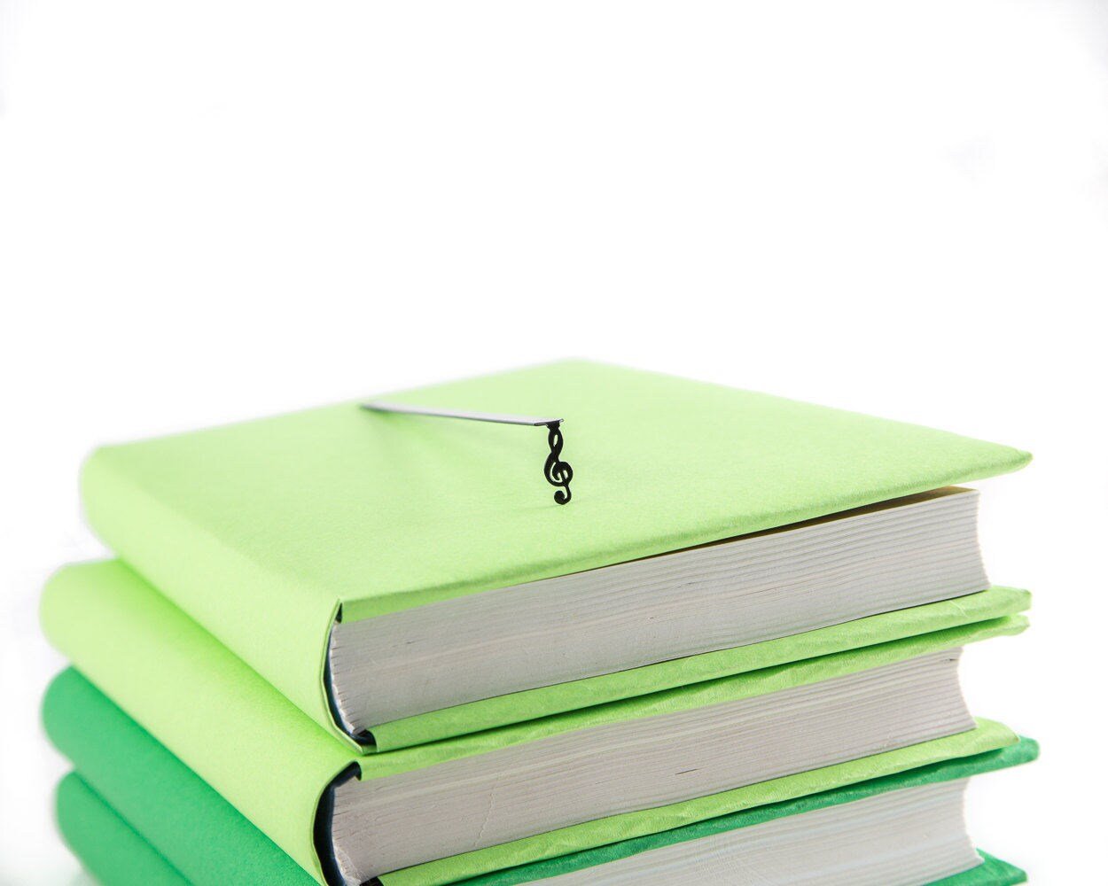 Treble Clef metal bookmark shown with a stack of books