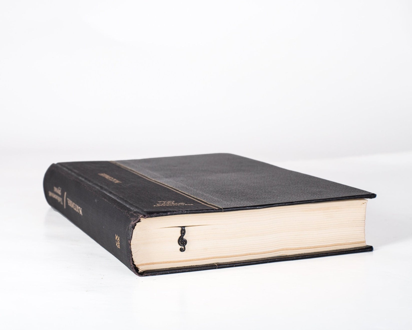 Treble Clef metal bookmark in a closed book, only its top showing above the pages