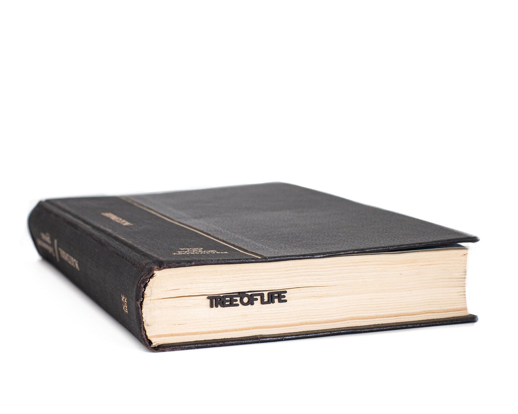 Tree of Life metal bookmark in a closed book, only its top showing above the pages