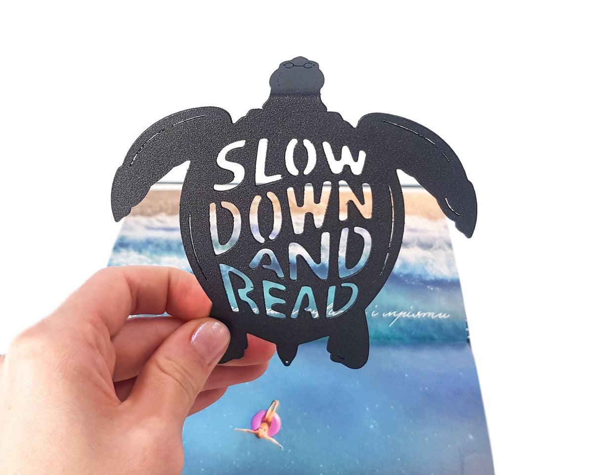 Turtle metal bookmark marking a page in an illustrated book