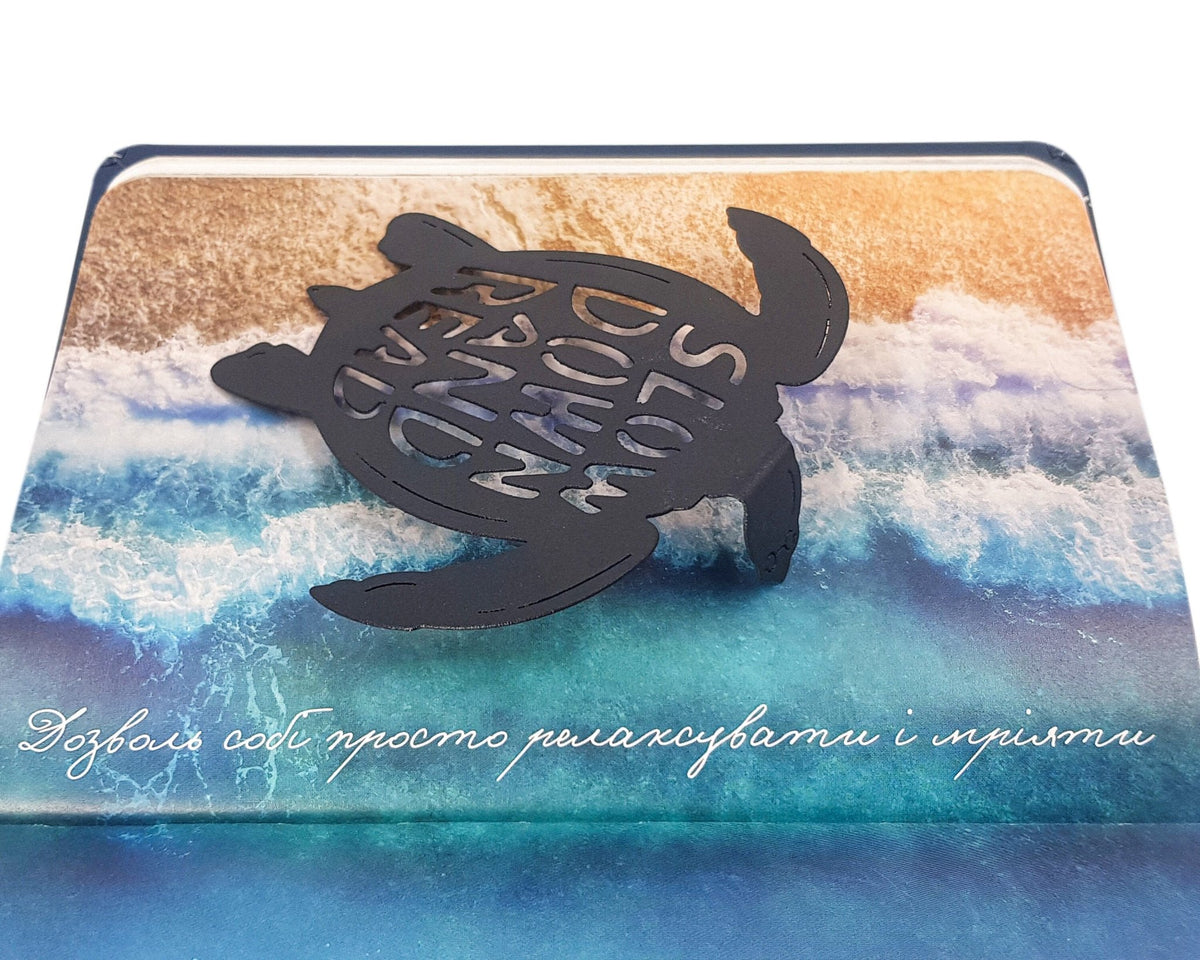 Turtle metal bookmark on an illustrated page