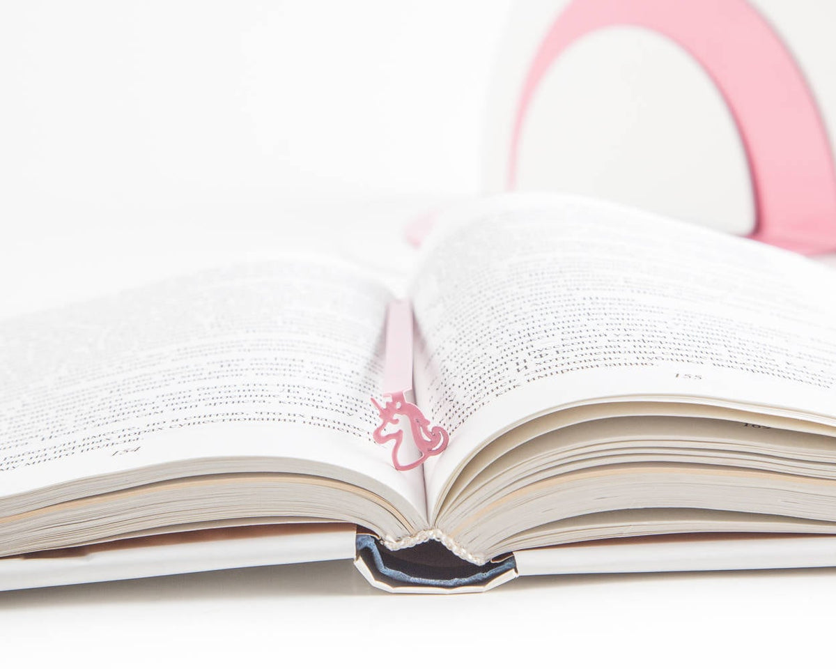 Unicorn metal bookmark in red resting on the pages of an open book