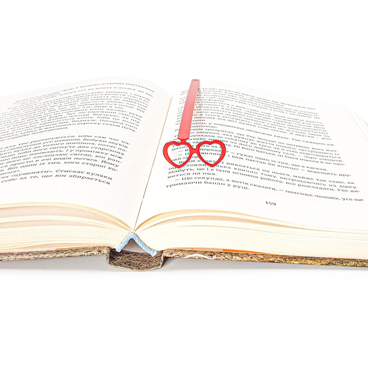 Vision Love metal bookmark in red resting on the pages of an open book