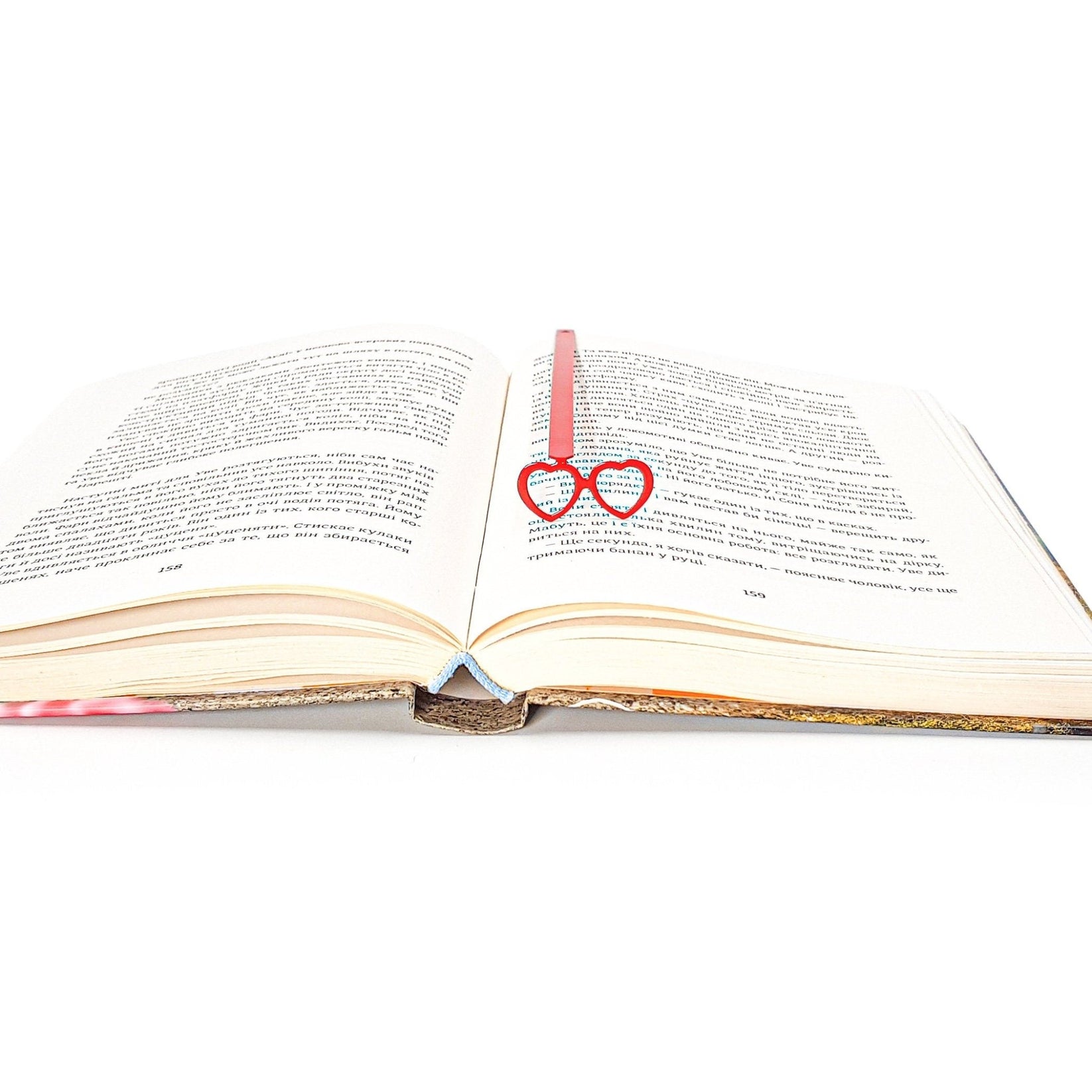 Vision Love metal bookmark in red marking a page in an open book