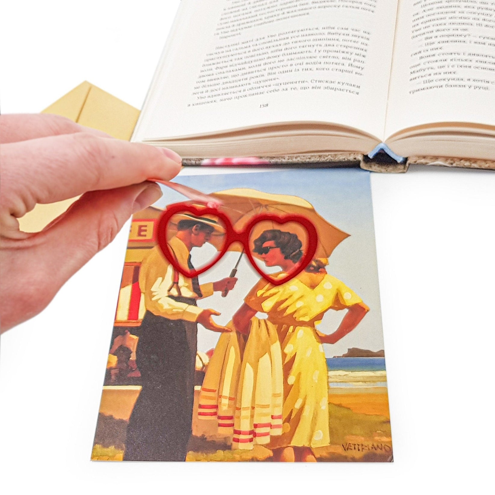 Vision Love metal bookmark in red marking a page in an illustrated book