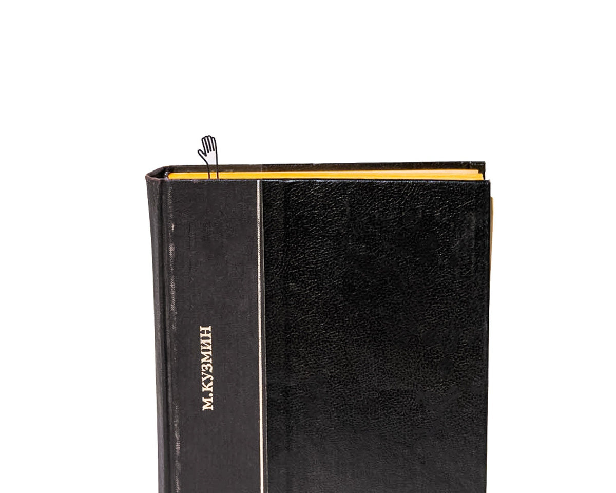 Waving Hand metal bookmark in a closed book, only its top showing above the pages