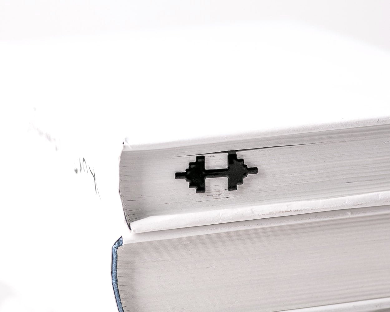 Weights metal bookmark in a closed book, only its top showing above the pages
