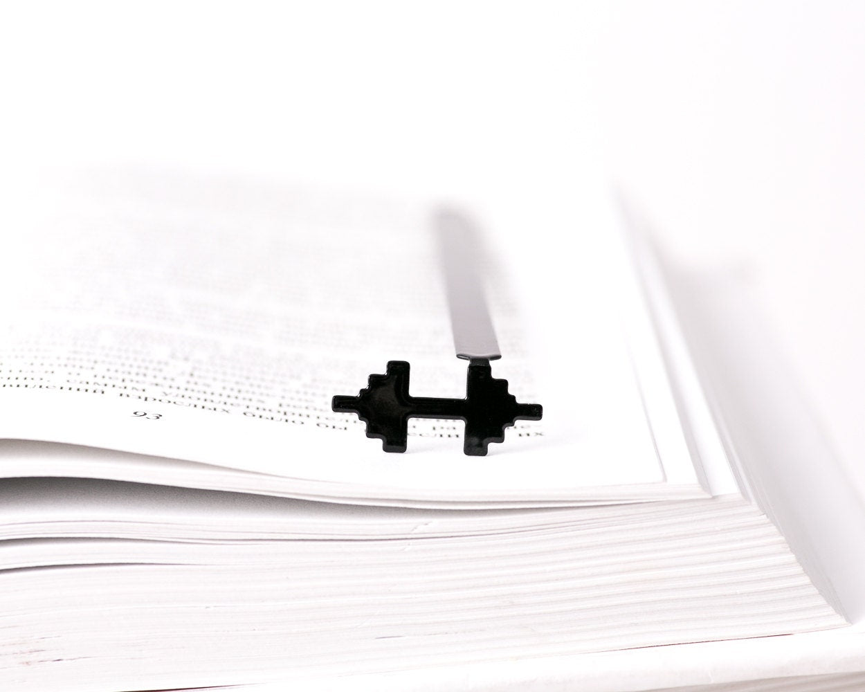 Weights metal bookmark resting on the pages of an open book