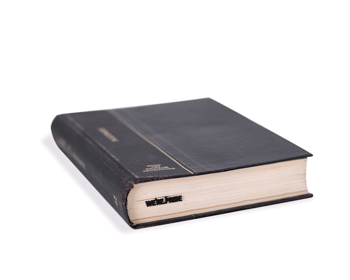 We're a Pride metal bookmark in a closed book, only its top showing above the pages