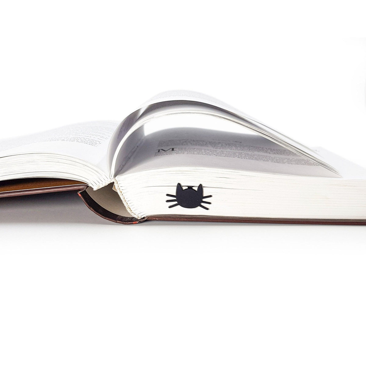 Whiskers in Your Book metal bookmark lying across the pages of an open book