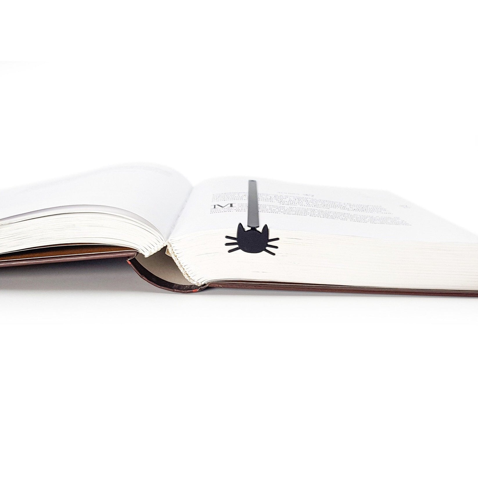 Whiskers in Your Book metal bookmark set into the gutter of an open book