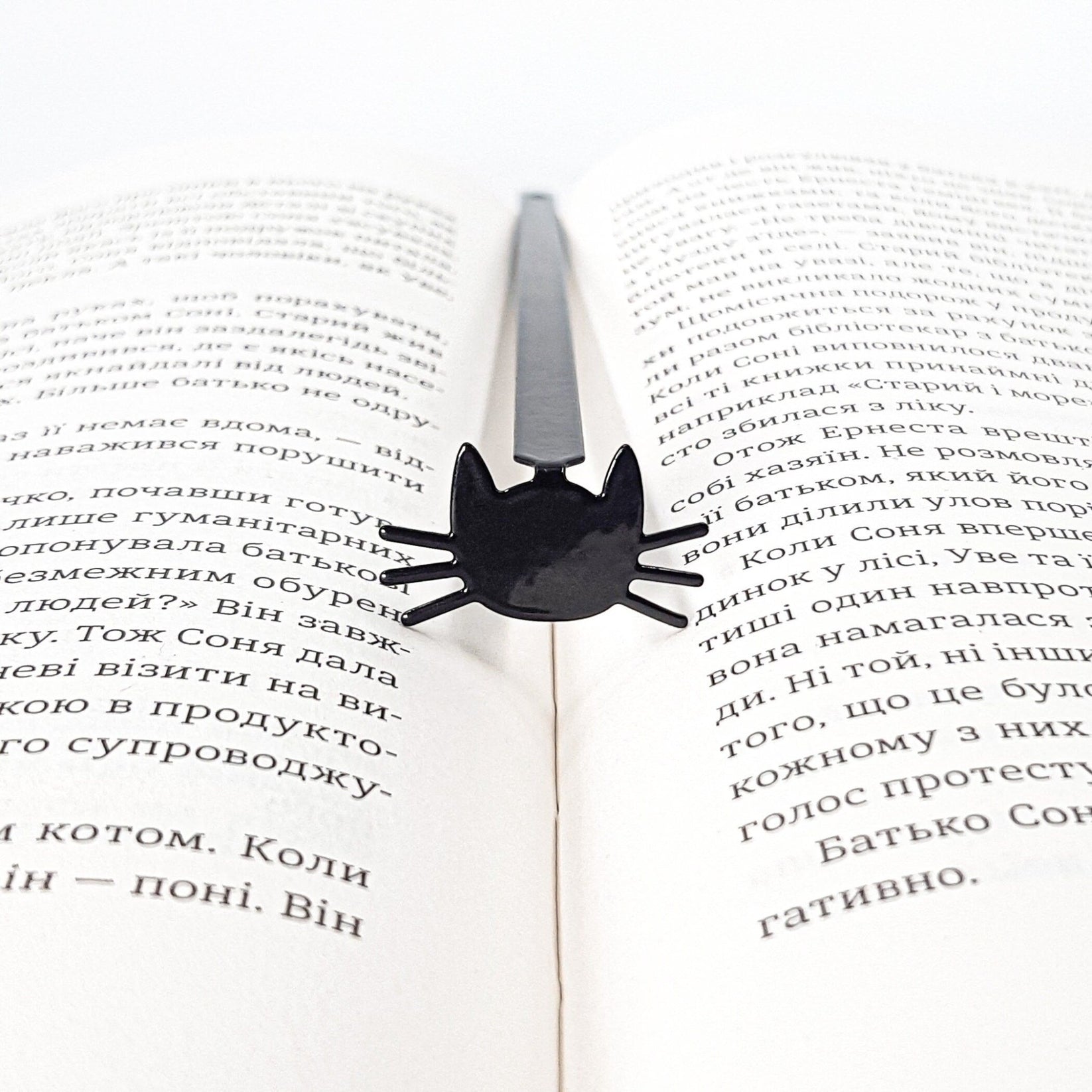 Whiskers in Your Book metal bookmark marking a page in an open book