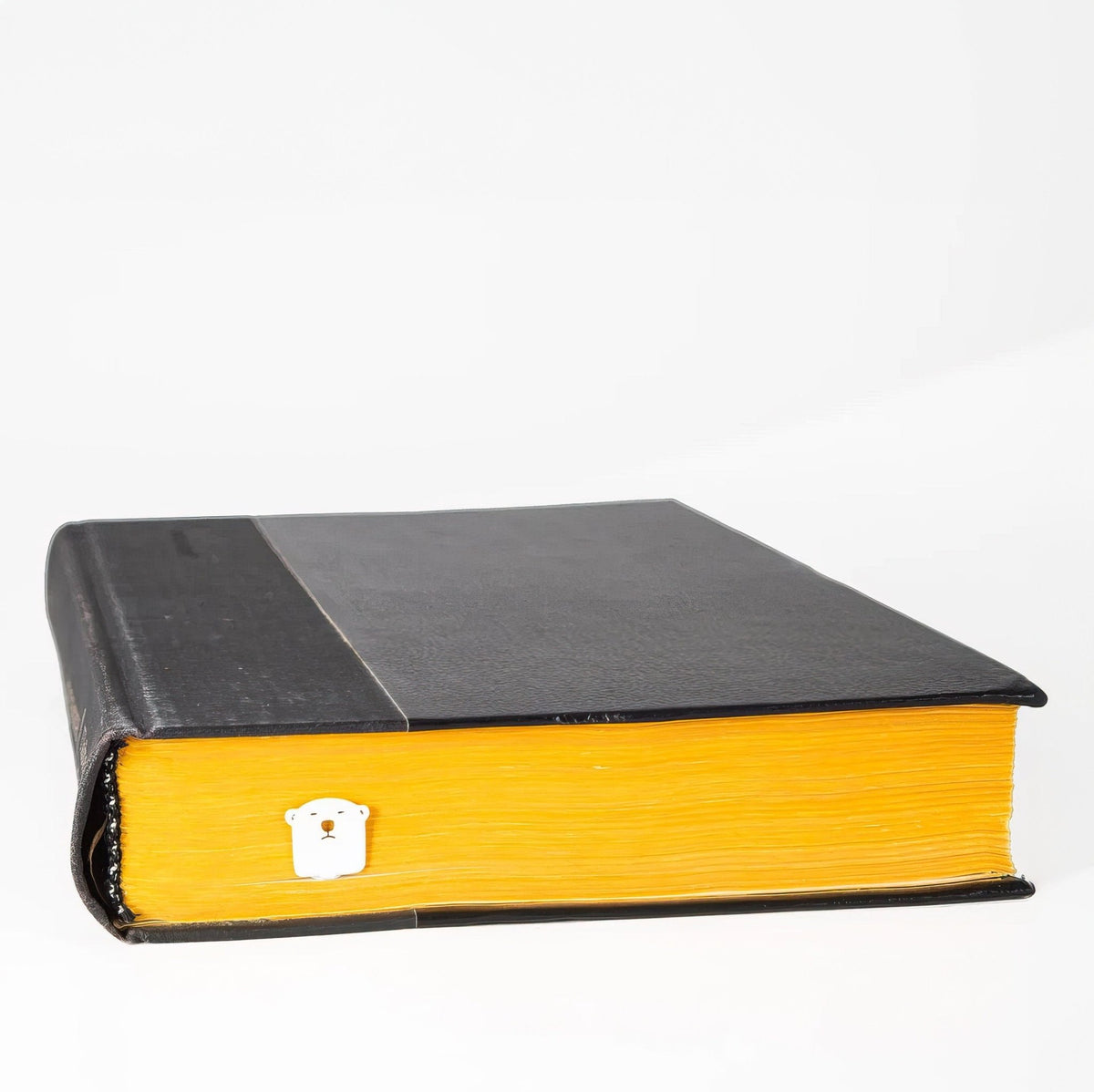 White Bear metal bookmark in white in a closed book, only its top showing above the pages