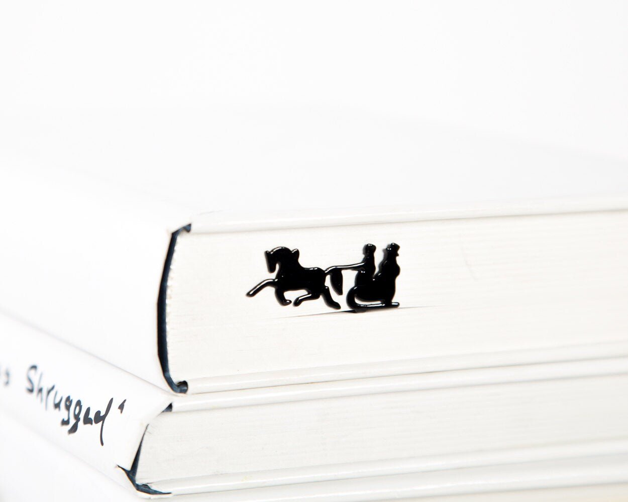 Winter Sleigh metal bookmark in a closed book, only its top showing above the pages
