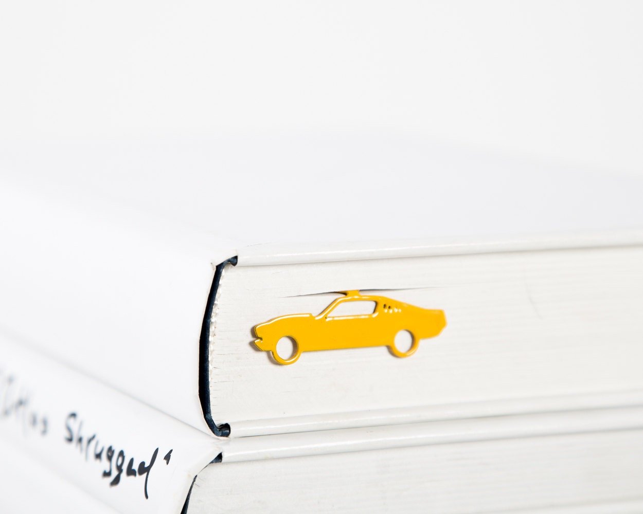Yellow Muscle Car metal bookmark in gold resting on the pages of an open book