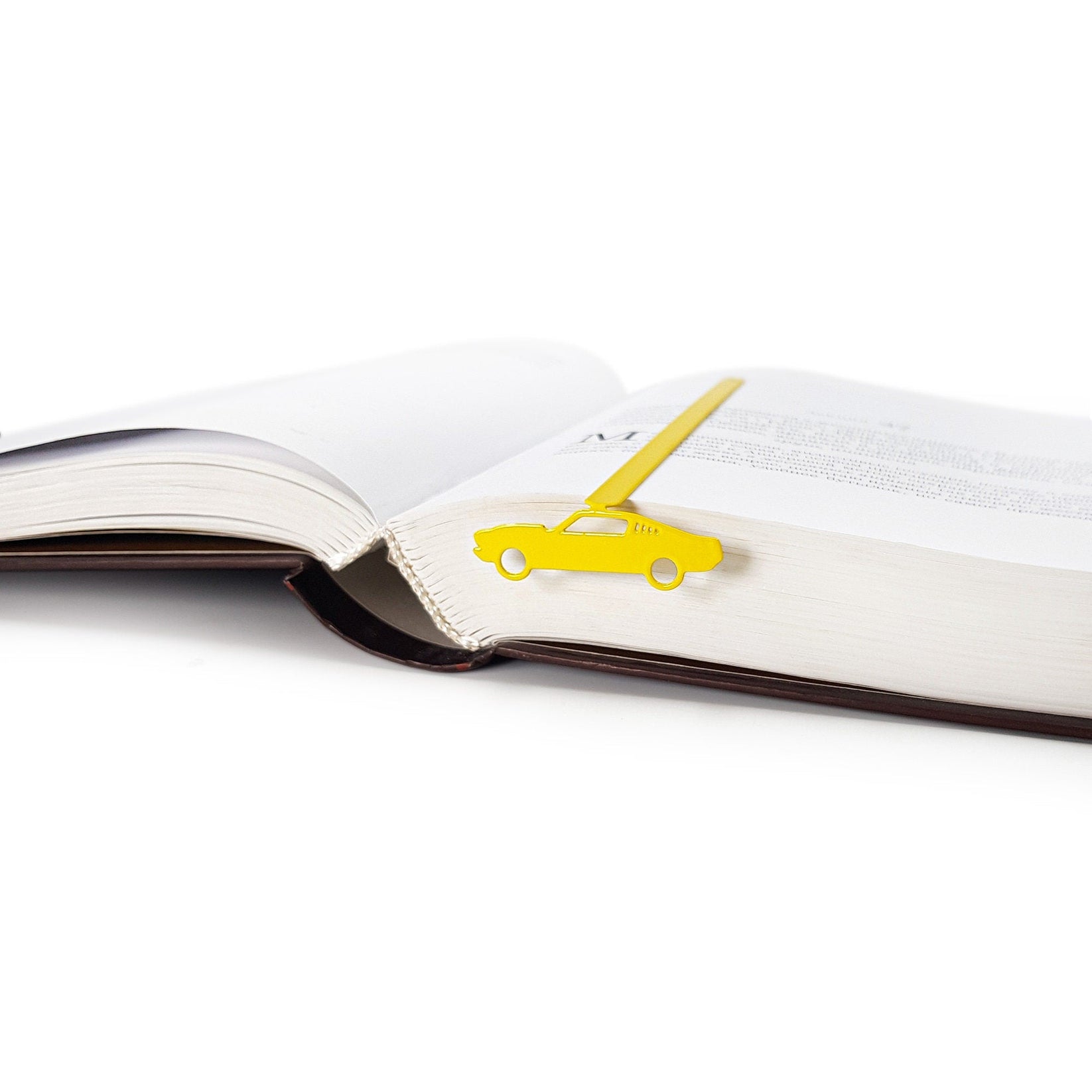 Yellow Muscle Car metal bookmark in gold lying across the pages of an open book